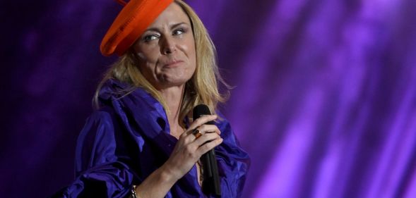 Singer-songwriter Róisín Murphy holds a microphone as she performs onstage in a purple outfit and with a red hat