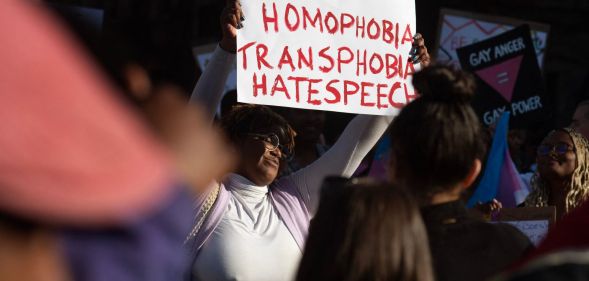 A person holds up a sign reading 'No homophobia, transphobia, hate speech' during a protest against Uganda's anti-LGBTQ+ bill