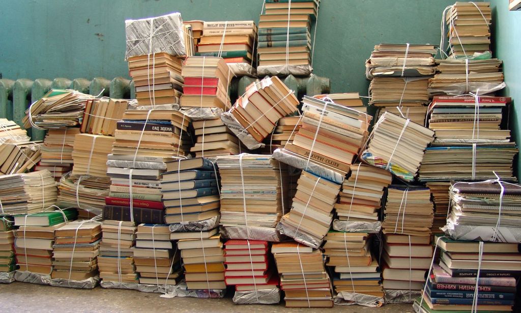 A pile of books tied up together in the corner of a room.