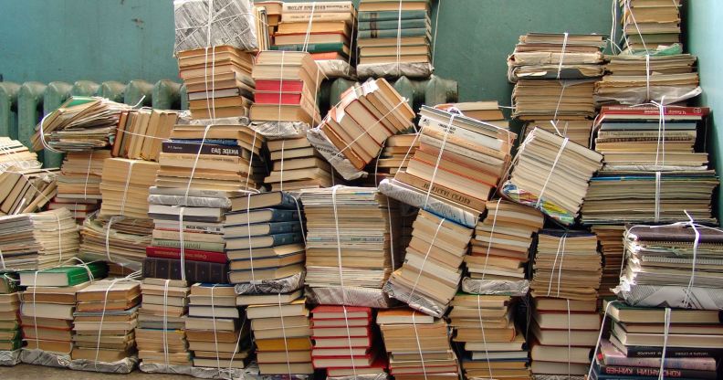 A pile of books tied up together in the corner of a room.