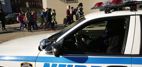 An NYPD police car next to a group of children heading to school.