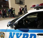 An NYPD police car next to a group of children heading to school.