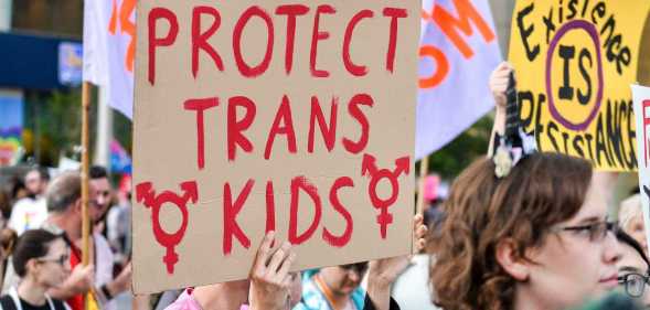 A protester holding a sign that reads 'protect trans kids'