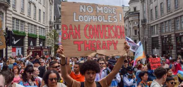 A protester holds a placard calling for a ban on conversion therapy