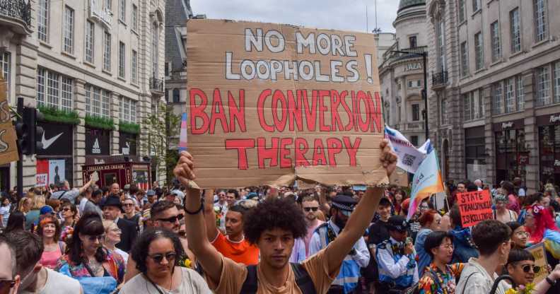 A protester holds a placard calling for a ban on conversion therapy