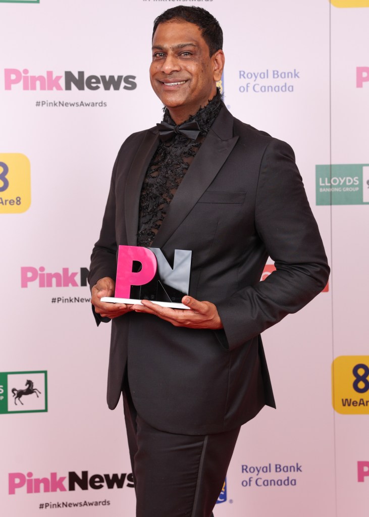 This is an image of a man holding up a PinkNews Award. 