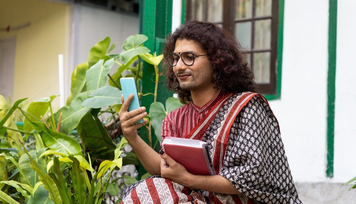 Stock photo of a transgender non-binary person using a mobile phone in an educational institute in India (Getty)