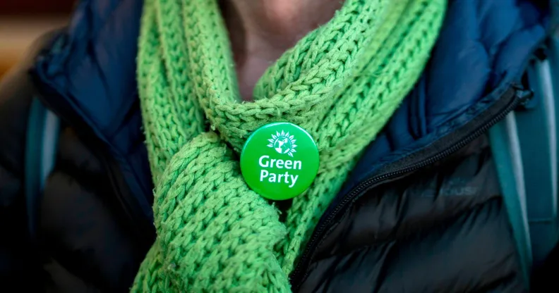 A Green Party member wearing a scarf and a Green Party badge.