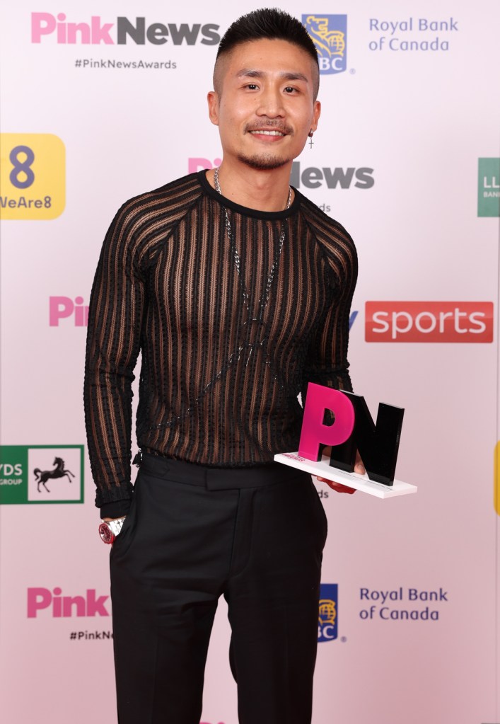 This is an image of a man posing with a PinkNews award