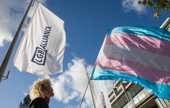 An LGB Alliance waves next to a trans flag.
