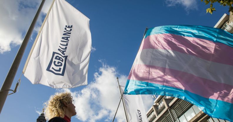 An LGB Alliance waves next to a trans flag.