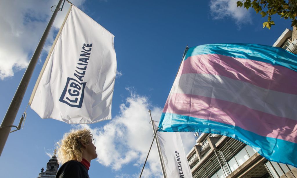 An LGB Alliance waves next to a trans flag.