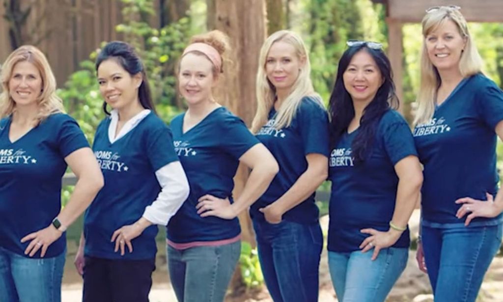 A group six women wearing Moms for Liberty shirts stand together for a photo.