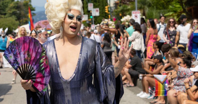A drag queen waves to a crowd during a Pride event.