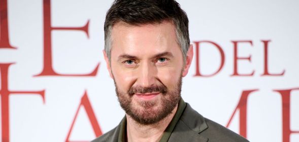Richard Armitage in a green shirt on the red carpet looking at the camera.