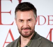 Richard Armitage in a green shirt on the red carpet looking at the camera.