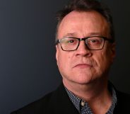 A headshot of Russell T Davies infront of a grey background.