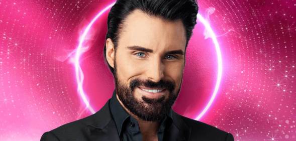 This is an image of Rylan Clark. He has dark hair, a short beard. He is wearing a black suit and is smiling.