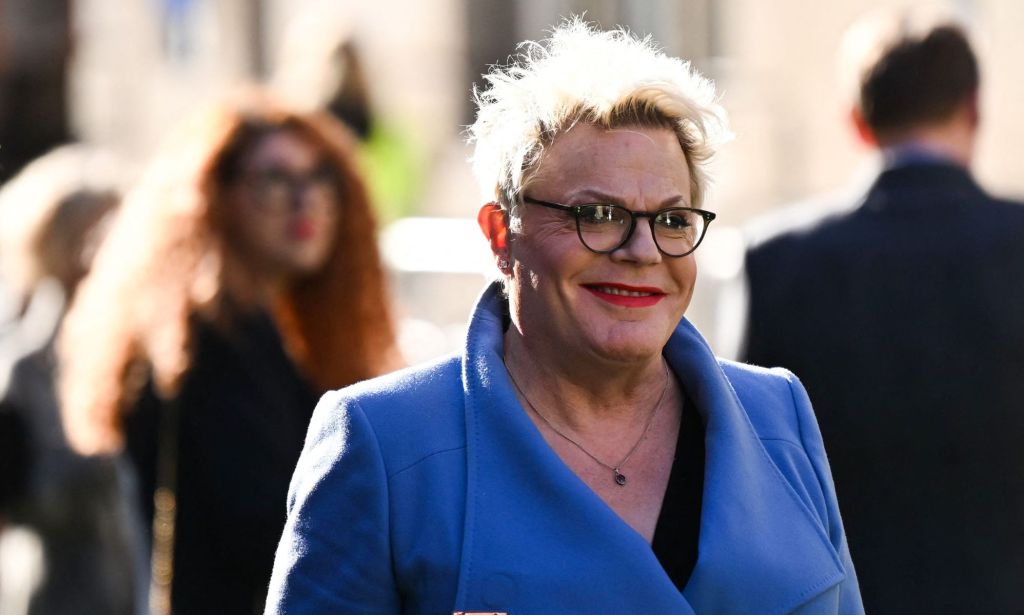 Comedian Suzy Eddie Izzard wearing a blue coat and red lipstick