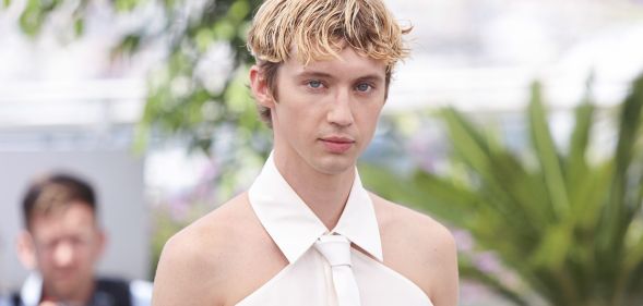 Troye Sivan in a white shoulder-less shirt.