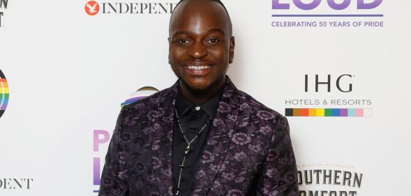 Will Njobvu in a patterned black and purple suit.