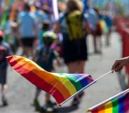A person holds a small LGBTQ+ Pride flag on a stick during a Pride parade.