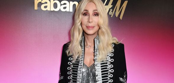Pop singer Cher wears a silver corset type top with a silver, grey and black jacket and long blonde hair