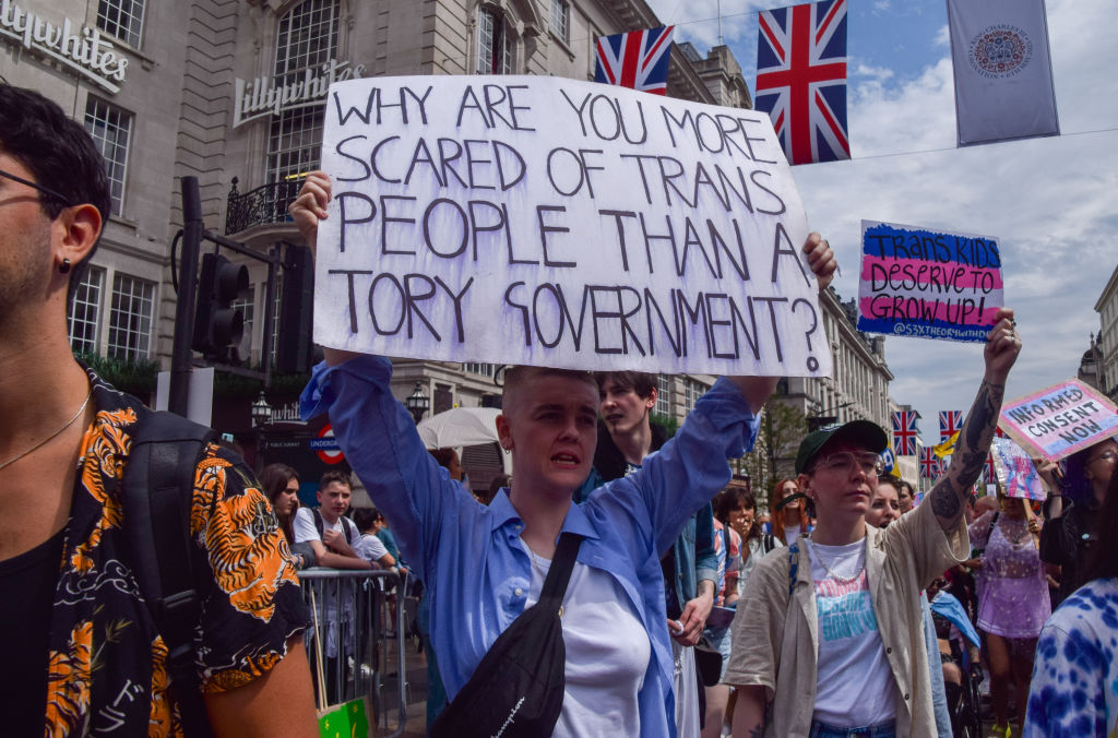 A protester holds a placard which states 'Why are you more scared of trans people than a Tory Government?' 