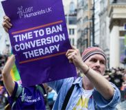 A protestor holds a sign reading "time to ban conversion therapy."