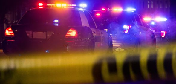 Two police cars driving away from police tape.