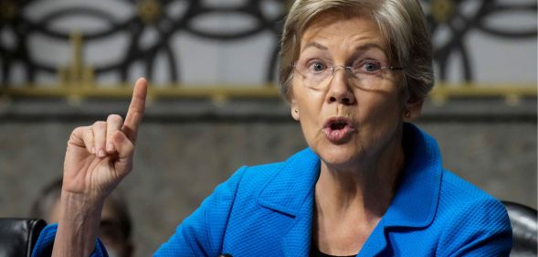 Elizabeth Warren raises a finger to enunciate a point while speaking.