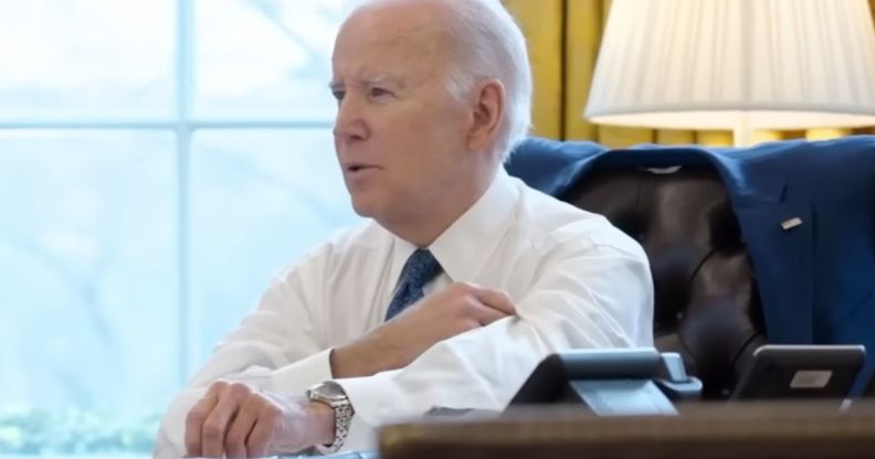 Joe Biden rolling up his sleeves whilst sat at the White House desk.