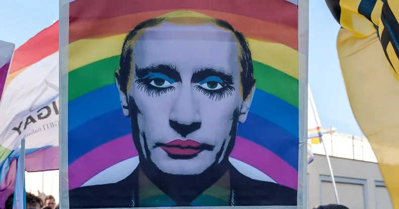 A protestor holding up a modified picture of Vladimir Putin wearing makeup.