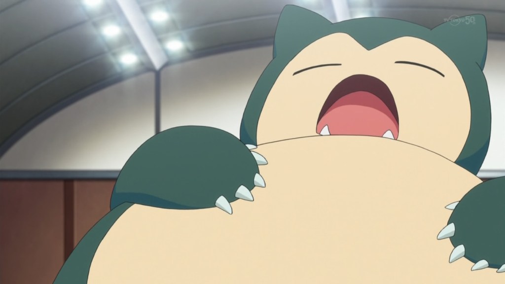 Picture of Snorlax, a large, bear-like Pokemon, blue and white in colour with pointed, cat like ears. It is yawning.