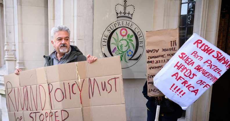 Activists hold posters with messages opposed to the Rwanda plan outside the Supreme Court.