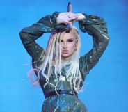 Kim Petras wears a sparkly outfit onstage as she holds a microphone above her head