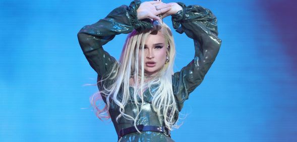 Kim Petras wears a sparkly outfit onstage as she holds a microphone above her head