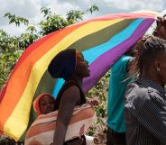 LGBTQ+ refugees from Uganda and other African countries walk together outside while they are living in Kenya and waving a rainbow flag