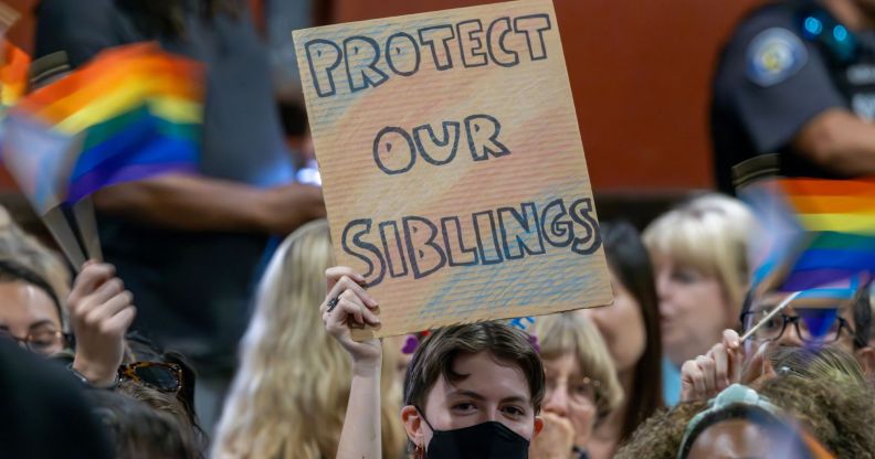 A person holds up a sign reading 'Protect our siblings' with the colours of the trans flag on the sign as they protest anti-trans policies championed by conservative groups and lawmakers, including the 2024 Republican presidential candidates during the debates