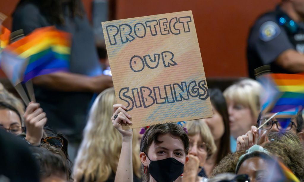 A person holds up a sign reading 'Protect our siblings' with the colours of the trans flag on the sign as they protest anti-trans policies championed by conservative groups and lawmakers, including the 2024 Republican presidential candidates during the debates