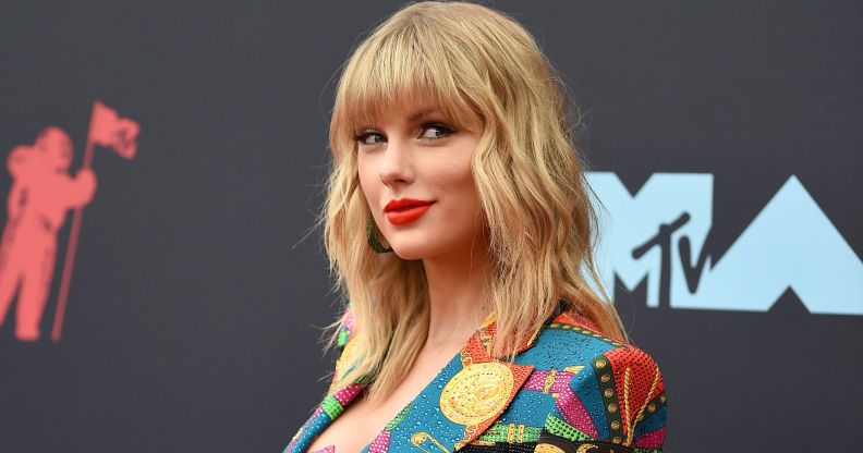 Taylor Swift on the red carpet wearing a patterned pastel blazer and bright red lip stick in 2019.