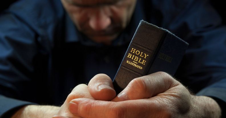 A man prays over a Bible.