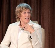 Lesbian swimmer Diana Nyad wears a cream suit while speaking on stage