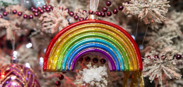 A Christmas ornament in the Shape of a rainbow on a festive Christmas tree