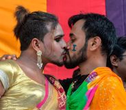 Two LGBTQ+ Indians kiss during a Pride parade.