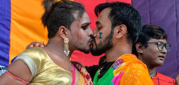 Two LGBTQ+ Indians kiss during a Pride parade.