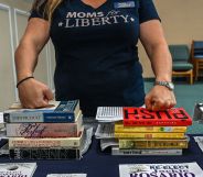 A Moms for Liberty member with her hands on two piles of books.