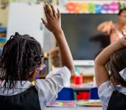 Two children raise their hands in a school classroom.