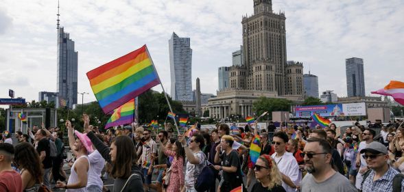 People march through the street with rainbow flags during the Warsaw Equality Parade in Poland in 2023