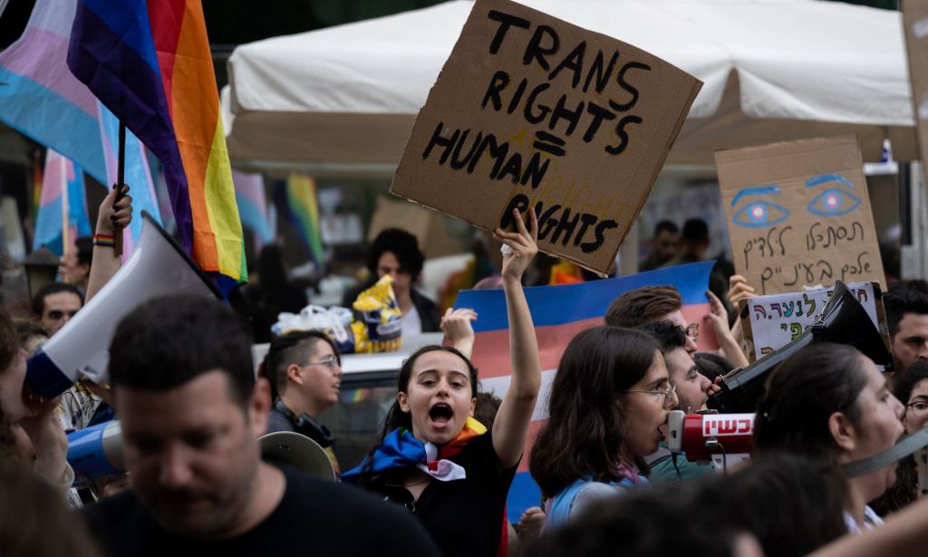 A person holds up a sign reading 'trans rights = human rights' outside an event for anti-trans author Abigail Shrier